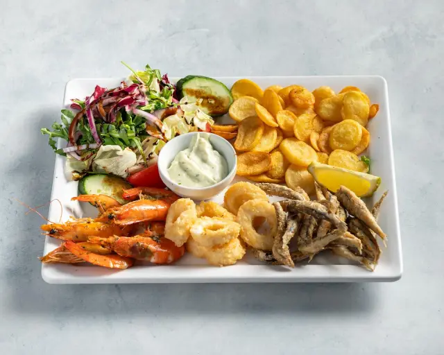 Teller mit Garnelen, Calamari-Ringen und Sardellen, dazu Kartoffelchips, Salat und Knoblauchdip
