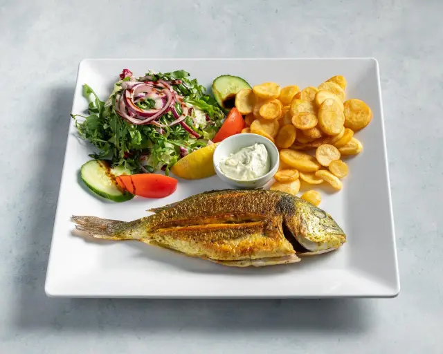 Ganzer Fisch vom Grill mit Kartoffelchips, Salat und Knoblauchdip